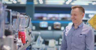 Aletleri mağaza genç yakışıklı adam onun mutfağı için blender seçer