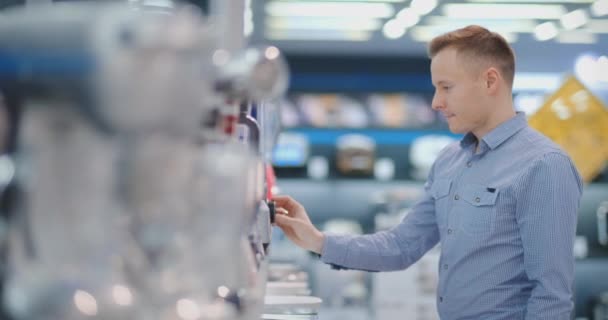 Jeune homme beau dans un magasin d'appareils électroménagers choisit mélangeur pour sa cuisine — Video