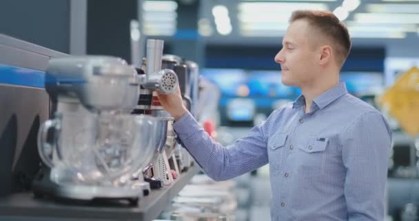 A man chooses a blender in the appliances store kitchen appliances in his hands and considers the design and characteristics — Stock Video