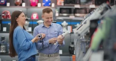 Aletleri mağazasında, çift etrafında kandırmak ve bir elektrik çarpması taklit eğlenmek. Deli adam ve kadın eğlenmek ve birbirlerine oynamak