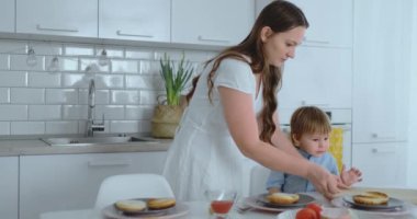 Genç Anne mutfakta hamburger pişirmek için bir çocuk yardımcı olur