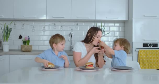 Crianças na cozinha alimentam sua mãe com hambúrgueres de dieta auto-cozidos — Vídeo de Stock