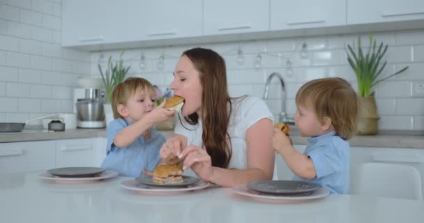 Children in the kitchen feed their mom with self-cooked diet burgers — Stock Video