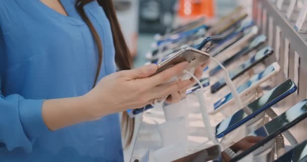 Close-up van dames hand kiezen voor het kopen van een nieuwe slimme telefoon in de buurt van een etalage in een elektronica winkel — Stockvideo