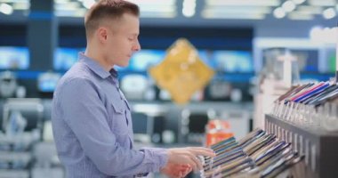 Akıllı telefonlar ile bir dükkan penceresinde duran bir adam taşınabilir bir elektronik mağaza satın almak için yeni bir telefon modeli seçer. Gadget 'ın en son sürümünü satın alın