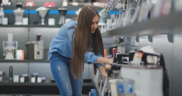 Dans le magasin d'appareils électroménagers, la femme choisit un mélangeur dans ses mains et considère le design et les caractéristiques . — Video