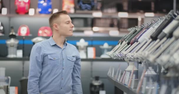 Un joven con camisa elige una licuadora para su cocina en una tienda de electrónica de consumo — Vídeo de stock