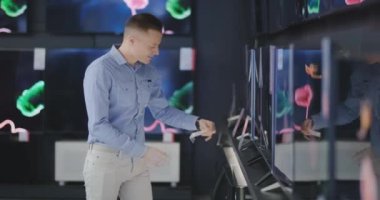 Teknoloji dükkanındaki adam yeni TV alışverişi yapıyor. yeni bir büyük ekran arıyorum. Alışveriş Zamanı.