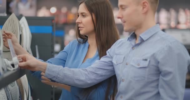 Familia pareja hermoso hombre y mujer elegir nuevo hierro en la tienda de electrónica de consumo — Vídeo de stock