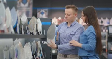 İki genç, evli bir çift bir erkek ve bir kadın ev eşyaları mağazasında yeni bir demir seçin