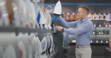 Genç yakışıklı bir adam yeni bir ev satın almak için mağazada demir inceler. Akıllı teknoloji demir seçimi