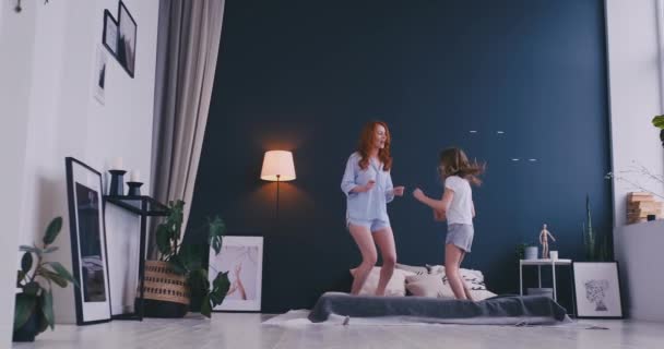 Mãe feliz e sua filha pulando na cama no quarto das crianças — Vídeo de Stock