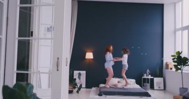 Mutlu aile, sevimli ve atlama ve yatakta dans genç annenin evde tatil sabahı sırasında eğlenin