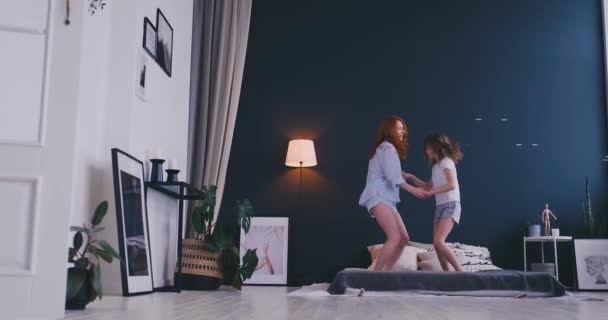 Mutter und Tochter springen auf dem Bett, glücklich, fröhlich — Stockvideo