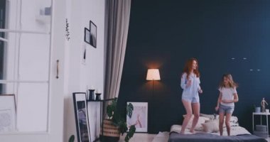 Sevimli ve atlama ve yatakta dans genç anne mutlu aileye sahip eğlenceli tatil sırasında evde