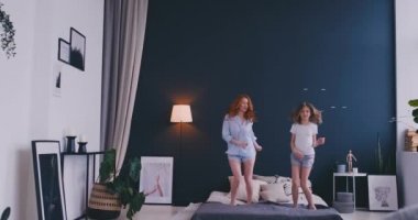 Güzel anne ve kızı evde yatakta atlama sırasında eğleniyor musun