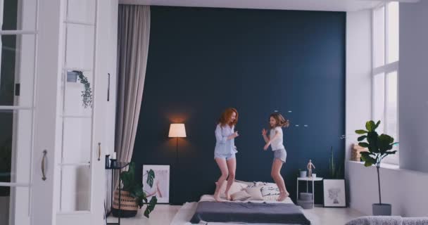 행복 한 어머니와 그녀의 딸 아이 방에 침대에 점프 — 비디오
