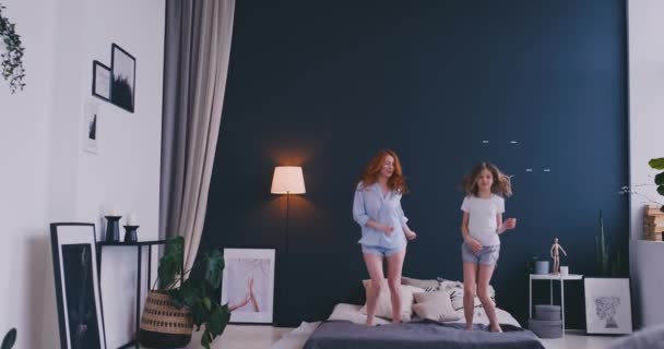 Mooie moeder en dochter zijn het hebben van pret terwijl het springen op bed thuis — Stockvideo