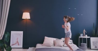 Kulaklık ile müzik dinlemek ve ebeveyn yatağında dans küçük bir kız portresi. Konsept: Müzik, özgürlük, mutluluk