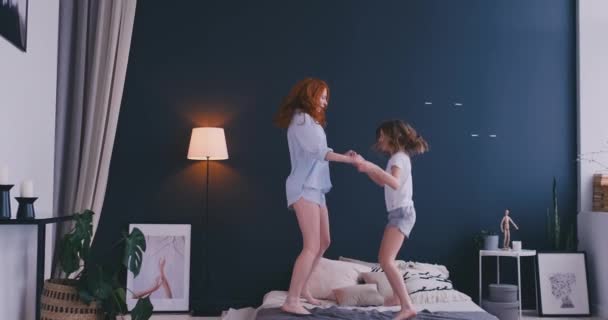 Belle maman et fille s'amusent tout en sautant sur le lit à la maison — Video