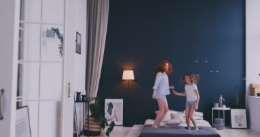 Mutlu aile, sevimli ve atlama ve yatakta dans genç annenin evde tatil sabahı sırasında eğlenin