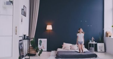 Kulaklık ile müzik dinlemek ve ebeveyn yatağında dans küçük bir kız portresi. Konsept: Müzik, özgürlük, mutluluk