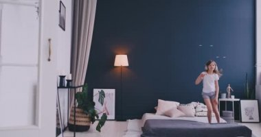 Kulaklık ile müzik dinlemek ve ebeveyn yatağında dans küçük bir kız portresi. Konsept: Müzik, özgürlük, mutluluk