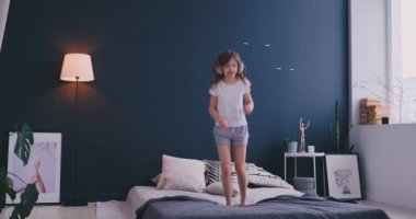 Kulaklık ile müzik dinlemek ve ebeveyn yatağında dans küçük bir kız portresi. Konsept: Müzik, özgürlük, mutluluk