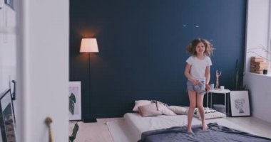 Kulaklık ile müzik dinlemek ve ebeveyn yatağında dans küçük bir kız portresi. Konsept: Müzik, özgürlük, mutluluk