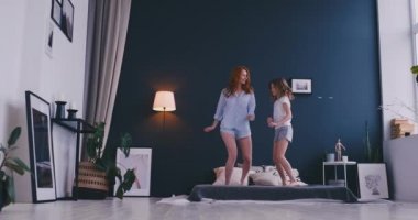 Mutlu aile, sevimli ve atlama ve yatakta dans genç annenin evde tatil sabahı sırasında eğlenin