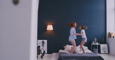 Mutlu aile, sevimli ve atlama ve yatakta dans genç annenin evde tatil sabahı sırasında eğlenin