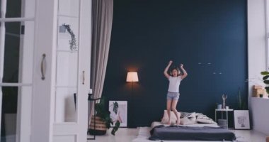 Kulaklık ile müzik dinlemek ve ebeveyn yatağında dans küçük bir kız portresi. Konsept: Müzik, özgürlük, mutluluk