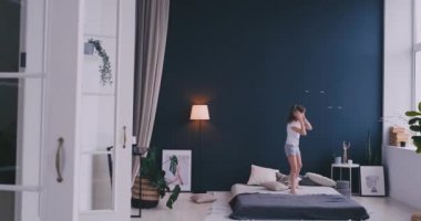Kulaklık ile müzik dinlemek ve ebeveyn yatağında dans küçük bir kız portresi. Konsept: Müzik, özgürlük, mutluluk