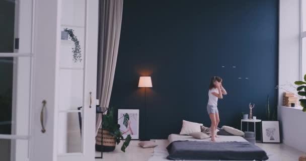 어린 소녀는 헤드폰으로 음악을 듣고와 그녀의 부모의 침대에 춤의 초상화. 개념: 음악, 자유, 행복 — 비디오