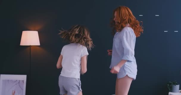 Щаслива мати і її дочка стрибають на ліжку в дитячій кімнаті — стокове відео
