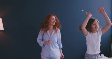 Güzel anne ve kızı evde yatakta atlama sırasında eğleniyor musun