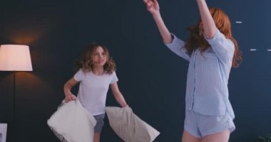 Mutlu anne büyük kız kardeşi ve kız çocuk keyfini komik yastık kavgası yatakta, bakıcı anne küçük çocuk kızıyla birlikte yatak odası, neşeli aile oyun birlikte sabah içinde gülüyor eğleniyor