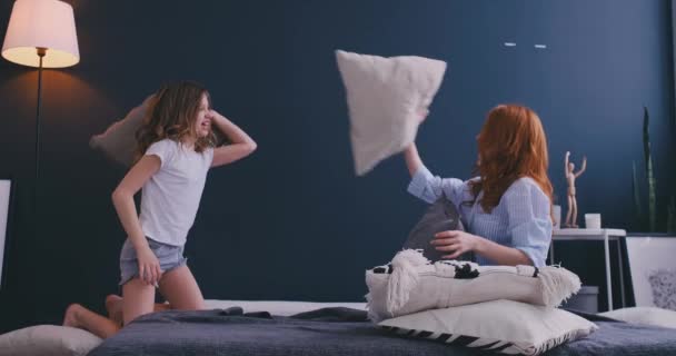 Gelukkig moeder oudere zus en kind meisje geniet van grappige kussengevecht op bed, oppas moeder met kind dochtertje samen plezier in de slaapkamer, vrolijke familie spelen lachen samen in de ochtend — Stockvideo