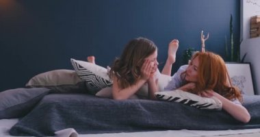 Komik overjoyed kız kardeşler yumuşak yastıklar üzerinde sabah yatakta yatarken eğlenmek mutlu hissediyor, anne ve kızı birlikte zaman zevk. Çocuk konsepti ile kapalı boş zaman aktiviteleri