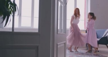 Mutlu sevgi dolu bir aile. Genç anne ve kızı çocuk odasında oynuyor. Anne ve kızı büyük bir pencerenin arka planda dans ediyor