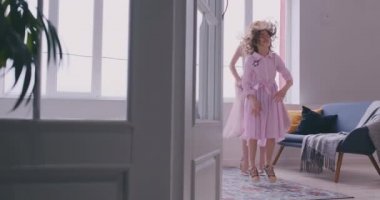 Mutlu sevgi dolu bir aile. Genç anne ve kızı çocuk odasında oynuyor. Anne ve kızı büyük bir pencerenin arka planda dans ediyor