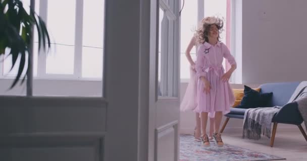 Glückliche liebende Familie. Die junge Mutter und ihre Tochter spielen im Kinderzimmer. Mutter und Tochter tanzen auf dem Hintergrund eines großen Fensters — Stockvideo