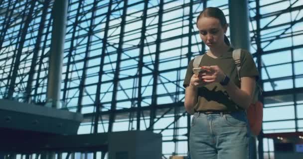 En kvinna tittar på skärmen på en mobiltelefon för att hitta din e-biljett på planet — Stockvideo