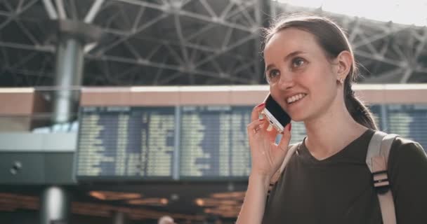 Vrouw reiziger praten aan de telefoon op het vliegveld en glimlachen — Stockvideo