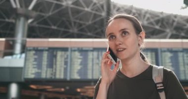 Havaalanında bir kadın telefonda uçuşunun gecikmesini tartışıyor.