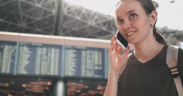 Девушка-путешественница в аэропорту, чтобы поговорить по мобильному телефону — стоковое видео
