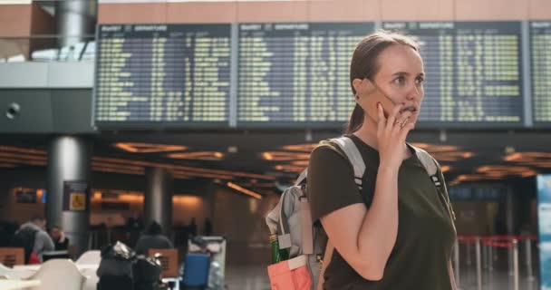 Молодая красивая женщина, стоящая в аэропорту, звонит по телефону — стоковое видео