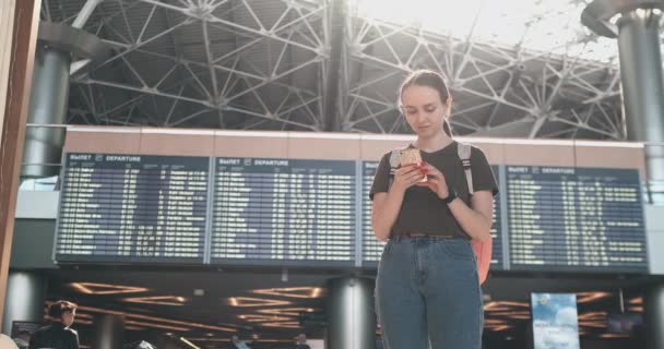 Νεαρή όμορφη γυναίκα στέκεται στο αεροδρόμιο γράφει ένα μήνυμα — Αρχείο Βίντεο