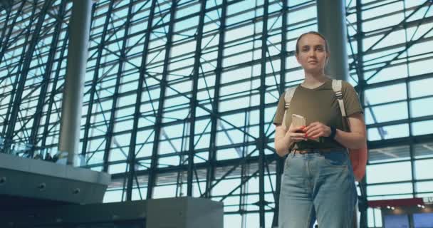 Eine junge Frau mit Rucksack am Flughafen schaut sich um — Stockvideo