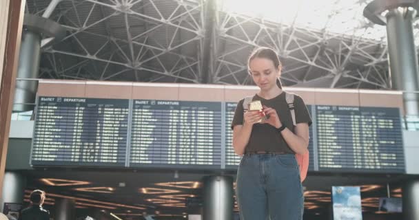 Νεαρή όμορφη γυναίκα στέκεται στο αεροδρόμιο γράφει ένα μήνυμα — Αρχείο Βίντεο